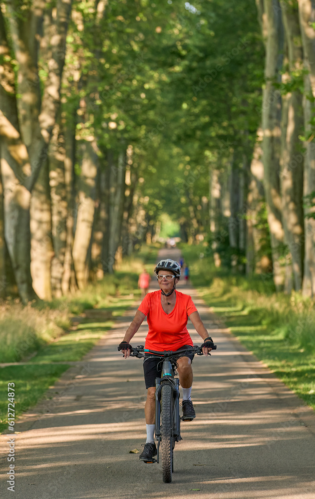 Naklejka premium attractive senior woman cycling with her electric mountain bike in the city park of Stuttgart, Baden-Wuerttemberg, Germany