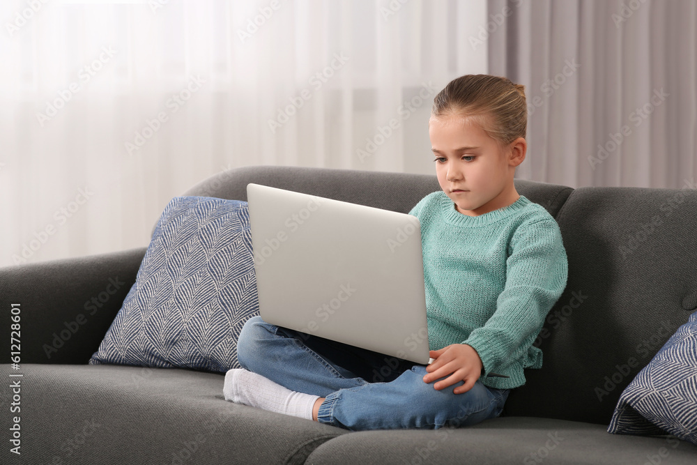 Little girl using laptop on sofa at home. Internet addiction Little girl using laptop on sofa at home. Internet addiction