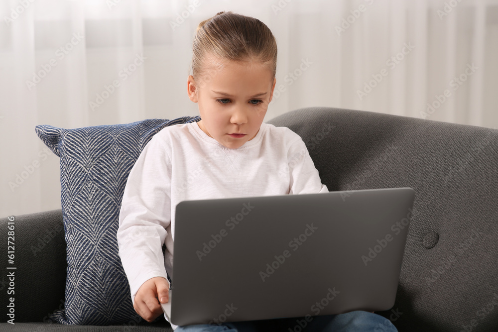 Little girl using laptop on sofa at home. Internet addiction Little girl using laptop on sofa at home. Internet addiction