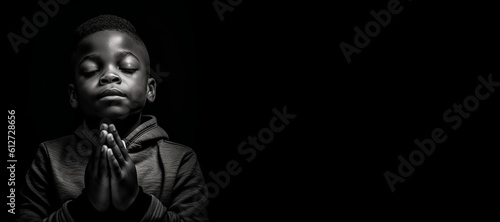 Black and white studio portrait of a young child praying banner on black background