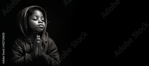 Black and white studio portrait of a young child praying banner on black background photo