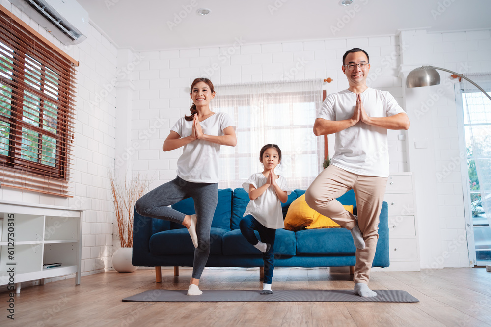 Obraz premium Family consisting of parents and daughters happily exercising together at home. For flexibility, build muscle strength, Sport Workout Training family together.