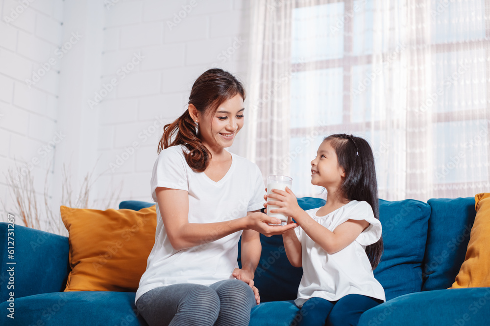 Mother give a glass of milk to lovely daughter, drinking milk at home to nourish healthy vitamins and strong teeth. Mother give a glass of milk to lovely daughter, drinking milk at home to nourish healthy vitamins and strong teeth.