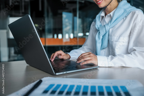 Young woman working at the office and typing on a laptop