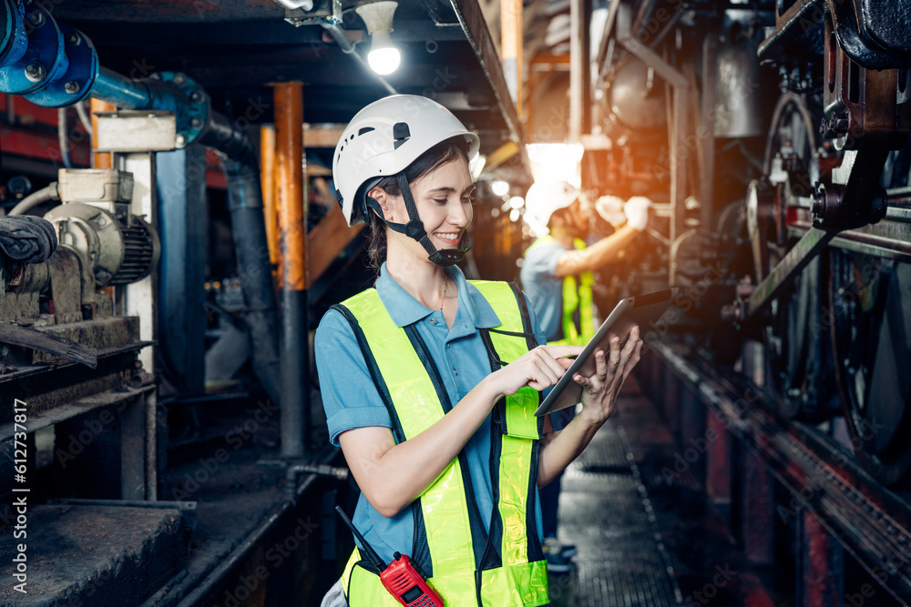 Portrait of professional woman engineer in white hardhat standing and holding tablet working in train factory.	