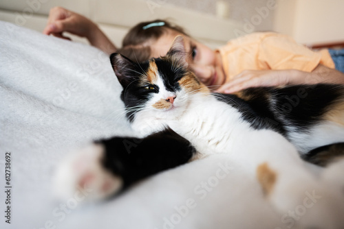 Cute little girl lying on the bed with her cat at home