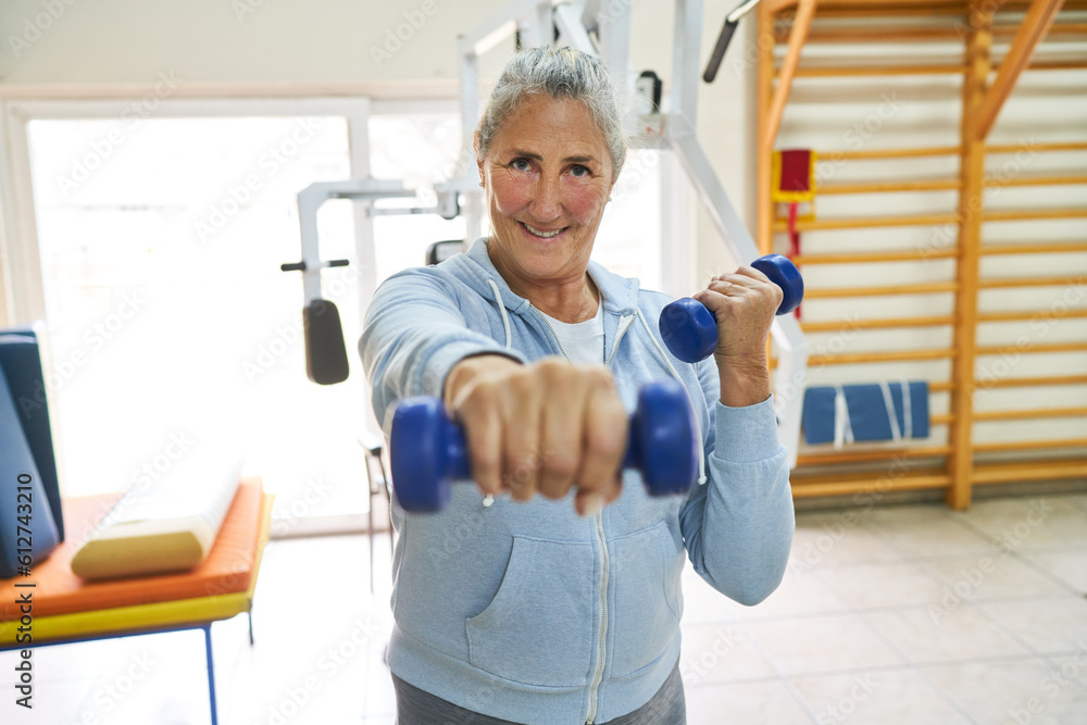 Senior woman exercising with dumbbells in rehab center Senior woman exercising with dumbbells in rehab center