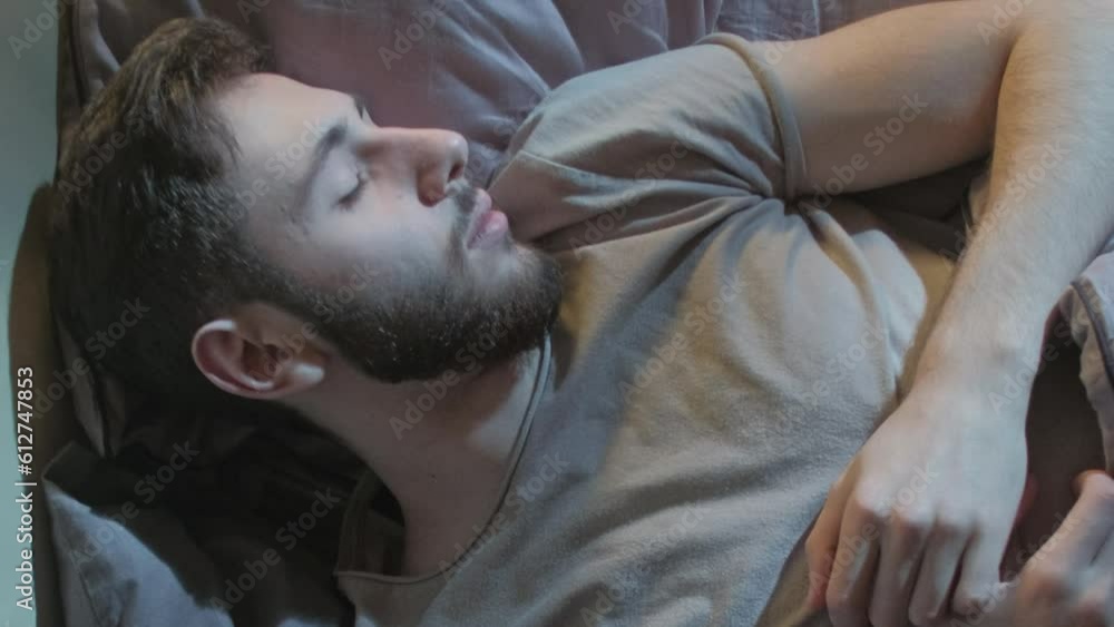Sleep disorder. Restless night. Bedtime anxiety Disturbed man dreaming nightmare tossing turning in bed in moonlight. Sleep disorder. Restless night. Bedtime anxiety Disturbed man dreaming nightmare tossing turning in bed in moonlight.