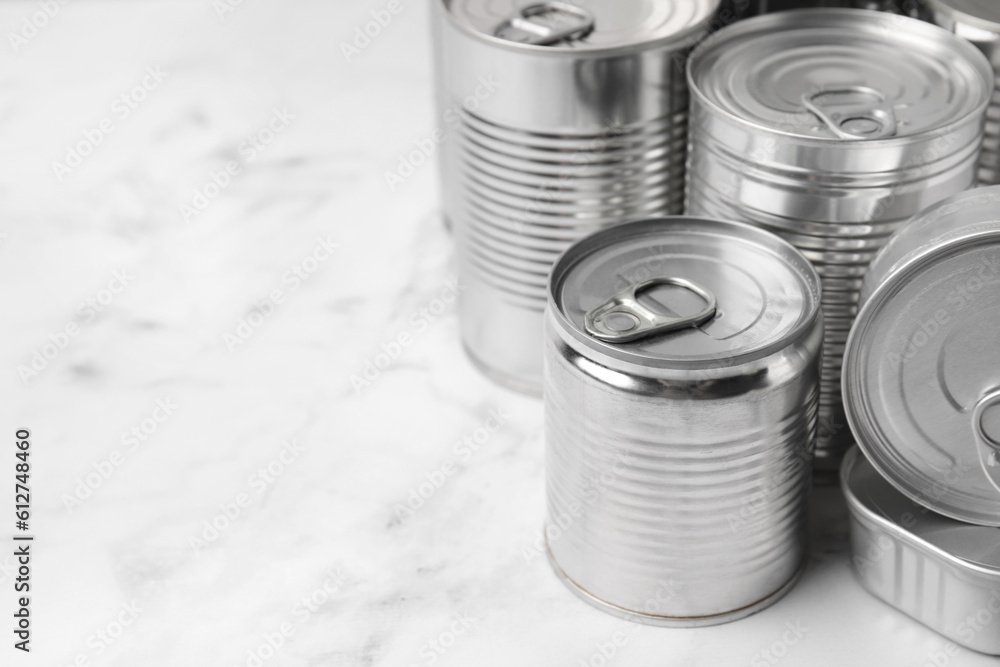 Many closed tin cans on white marble table, closeup. Space for text Many closed tin cans on white marble table, closeup. Space for text