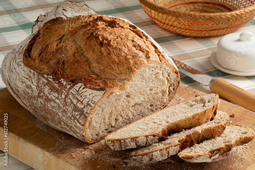 Fresh loaf and slices of sourdough farmers bread close up on a cutting board  