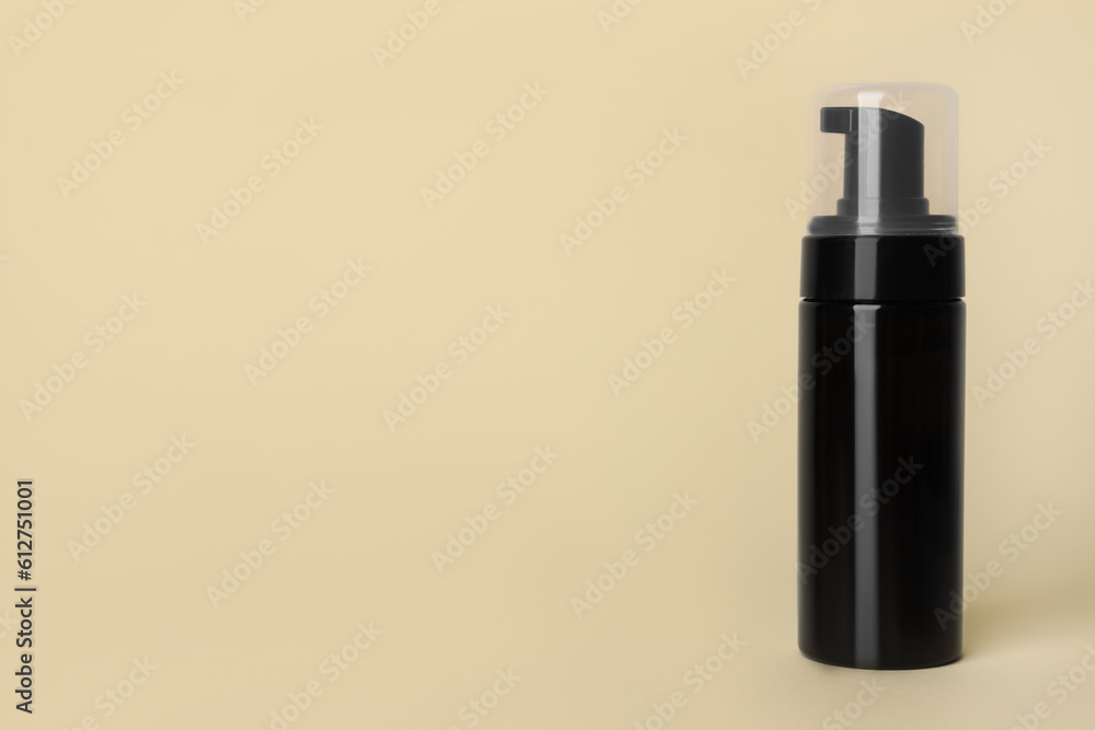 Bottle of face cleansing product on beige background. Space for text Bottle of face cleansing product on beige background. Space for text