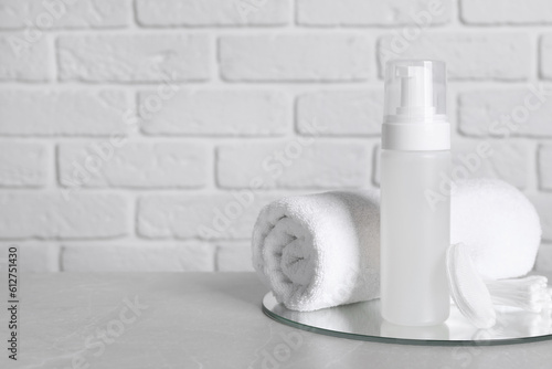 Bottle of face cleansing product  towel  cotton pads and buds on grey table. Space for text