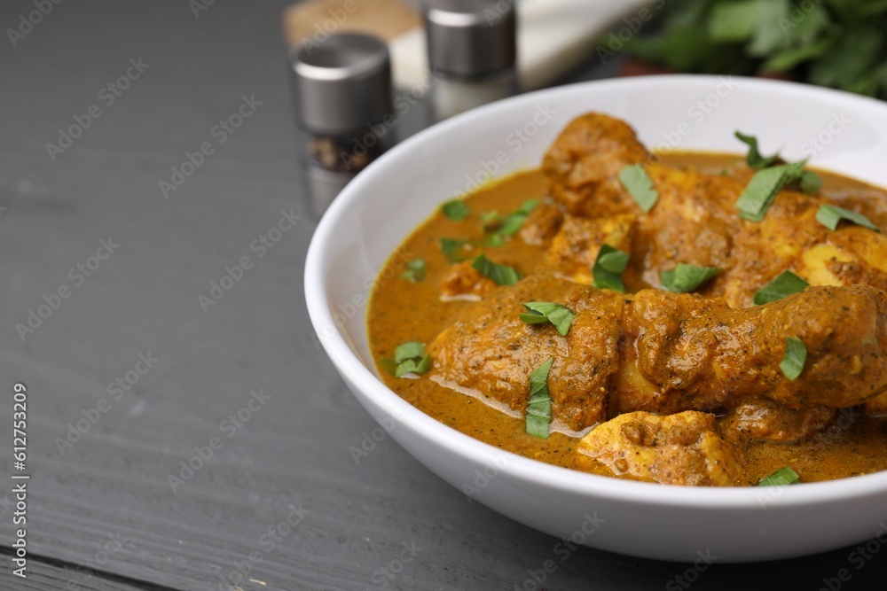Delicious chicken with curry sauce on grey wooden table, closeup. Space for text Delicious chicken with curry sauce on grey wooden table, closeup. Space for text
