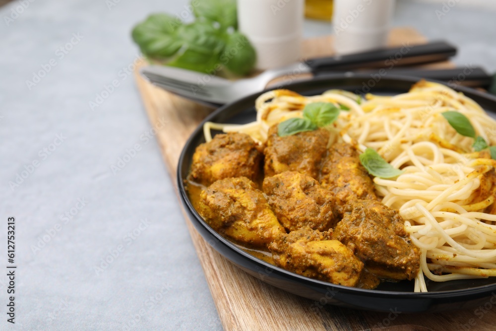 Delicious pasta and chicken with curry sauce served on grey table, closeup. Space for text Delicious pasta and chicken with curry sauce served on grey table, closeup. Space for text