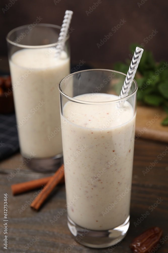 Glasses of delicious date smoothie, dried fruit and cinnamon sticks on wooden table, closeup Glasses of delicious date smoothie, dried fruit and cinnamon sticks on wooden table, closeup