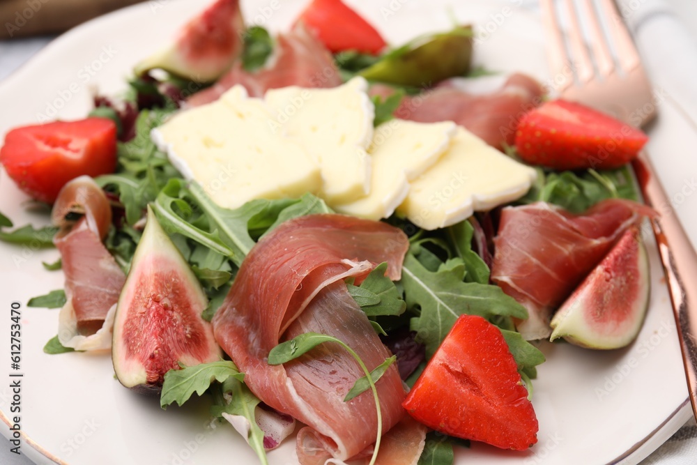 Tasty salad with brie cheese, prosciutto, strawberries and figs on white plate, closeup Tasty salad with brie cheese, prosciutto, strawberries and figs on white plate, closeup