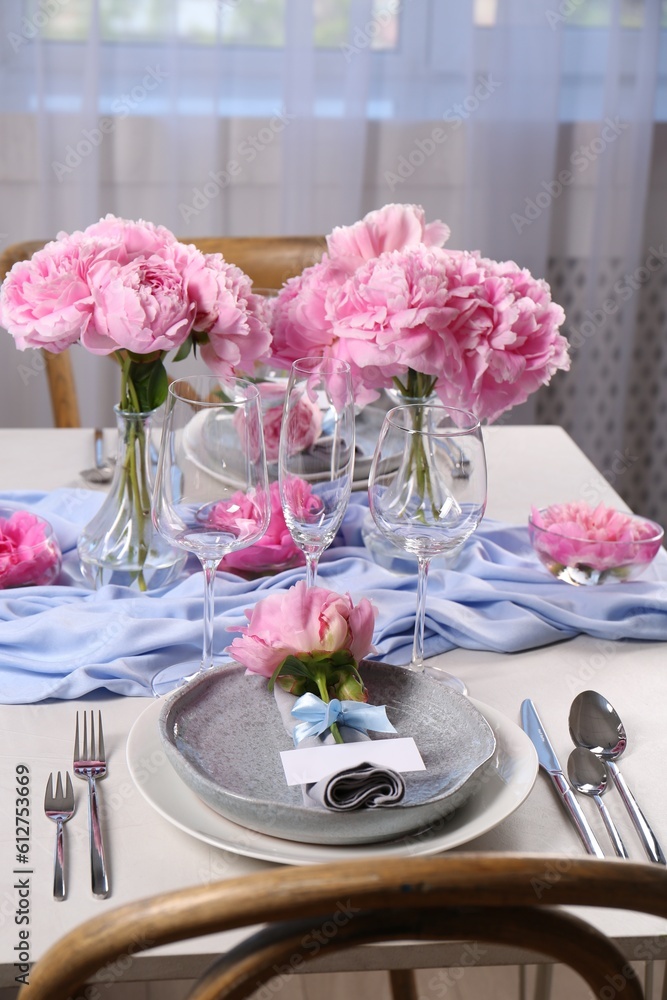 Stylish table setting with beautiful peonies, napkin and blank card indoors Stylish table setting with beautiful peonies, napkin and blank card indoors