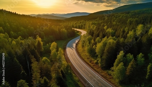 Drone view of a meandering road through forest at sunrise. car on the road.