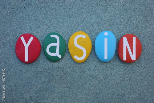 Yasin, turkish masculine given name composed with multi colored stone letters over green sand