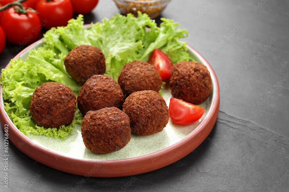 Delicious falafel balls, tomatoes and lettuce on dark table, closeup. Vegan meat products Delicious falafel balls, tomatoes and lettuce on dark table, closeup. Vegan meat products