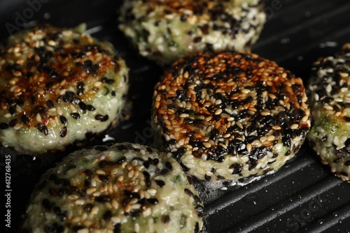 Cooking tasty vegan cutlets with sesame in grill pan, closeup