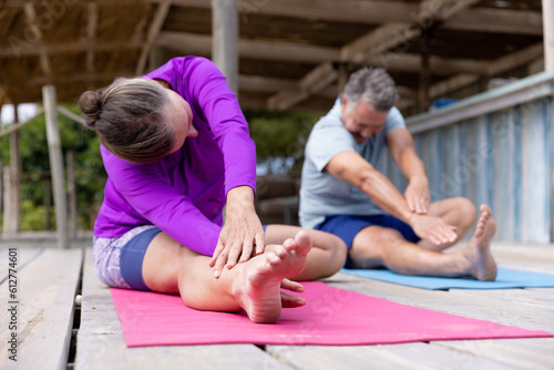 Caucasian senior couple stretching hands and legs while practicing yoga on floor at tourist resort © wavebreak3