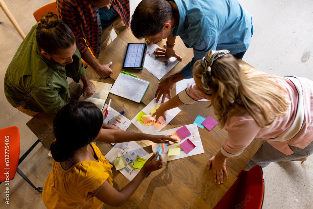 © WavebreakMediaMicro - High angle view of diverse creative colleagues in discussion brainstorming using notes and tablet