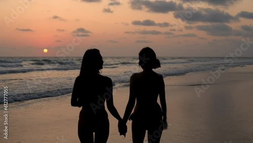 Holiday concept of 4k Resolution. The silhouette of two girls walking on the beach.