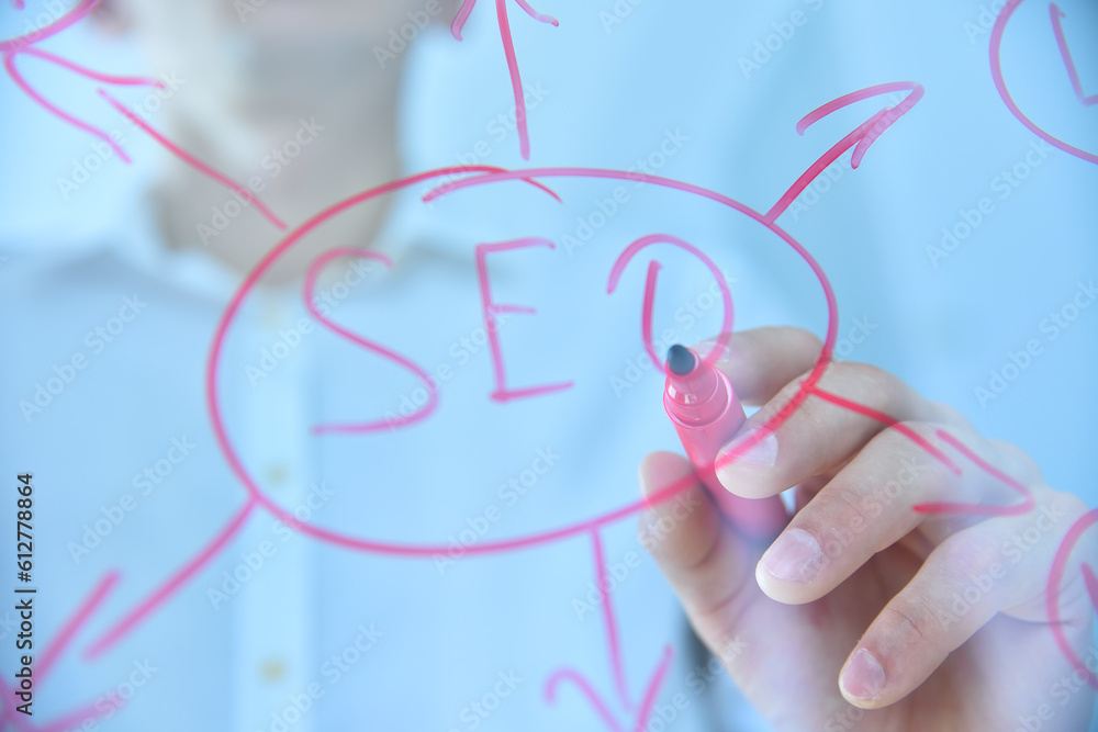 Hand with red pen writing SEO concep Hand with red pen writing SEO concep