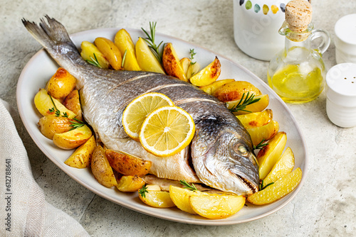 Meal with baked sea bream or dorada fish with baked potato, lemon and herbs. photo