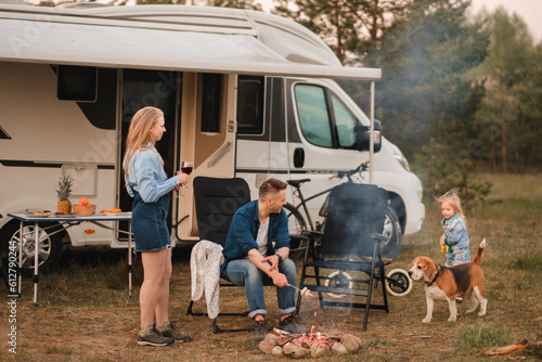 Foto A family cooks sausages on a bonfire near their motorhome in the woods