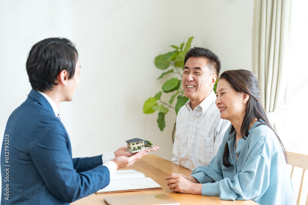 Fototapeta premium 住宅模型を持つ営業マンと日本人夫婦