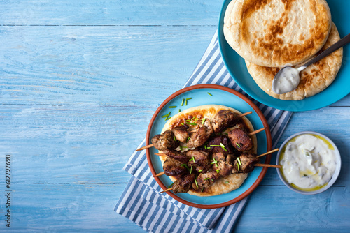 Greek souvlaki with pita bread and tzatziki sauce on a blue wooden background.Copy space