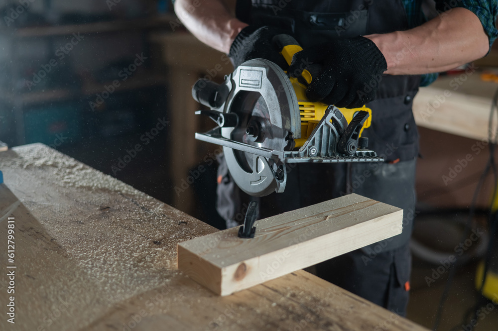 Master cuts the board with a circular saw in the workshop. Close-up of a carpenter's hands at work. Master cuts the board with a circular saw in the workshop. Close-up of a carpenter's hands at work.
