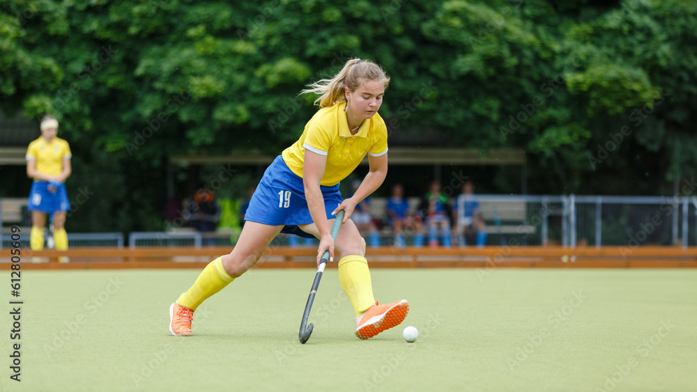 Field hockey female player leading the ball in attack. Young woman playing in field hockey tournament