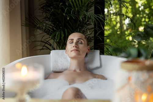 woman enjoying spa bath with foam and scented candles. body care, aromatherapy and mental wellness