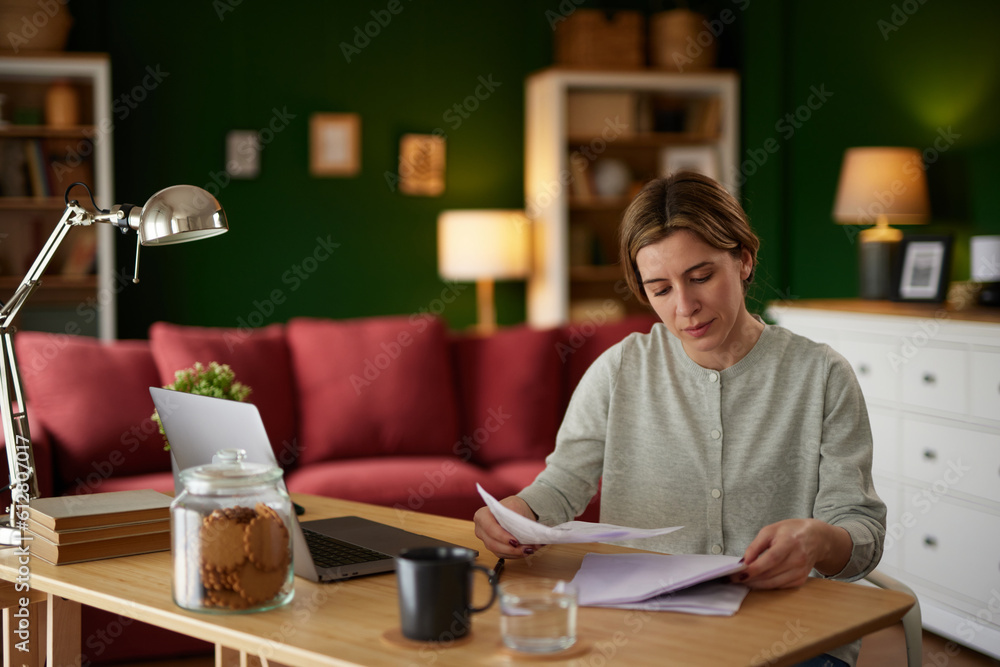 Mid adult woman examining her bank statement at home office