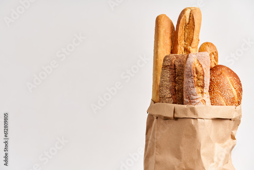 Different types of french bread baguettes in paper bag over white background with copy space