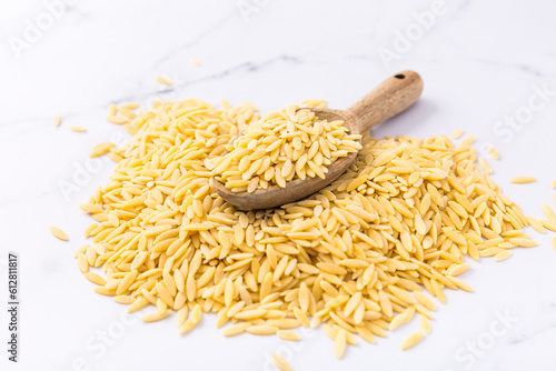 Raw orzo pasta (risoni) with wooden spoon photo