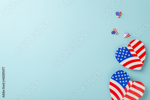 Patriotism celebration. Top view of emblematic decorations: flying hearts adorned with American flag pattern on a pastel blue backdrop featuring a blank circle for text or advertisements