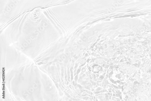 White water with ripples on the surface. Defocus blurred transparent white colored clear calm water surface texture with splashes and bubbles. Water waves with shining pattern texture background.