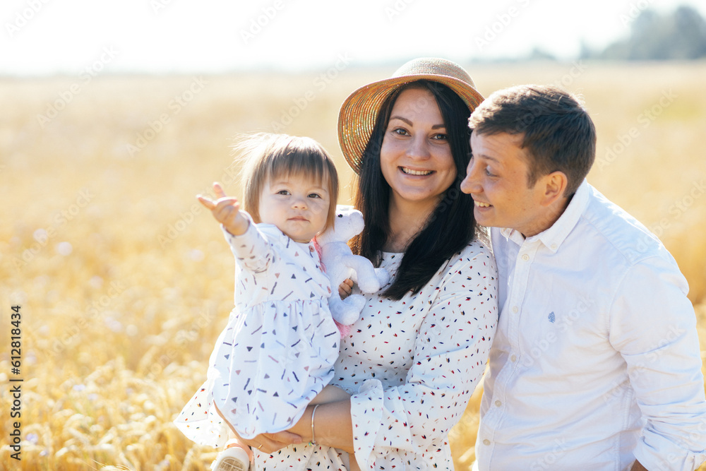 Happy family of three people hugging in the wheat field. The smiling faces of women, men and children. Children play with their parents. Happy family of three people hugging in the wheat field. The smiling faces of women, men and children. Children play with their parents.