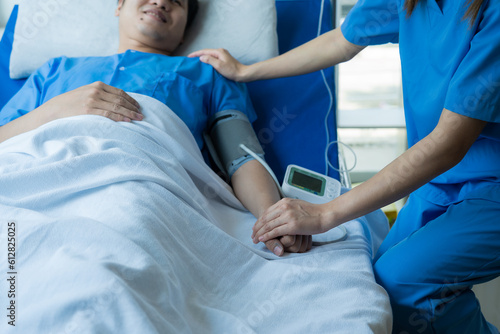 Two doctors talking to a patient lying in bed while receiving saline solution in hospital Professional medical service concept Attentive doctor comforting a patient Stock Picture