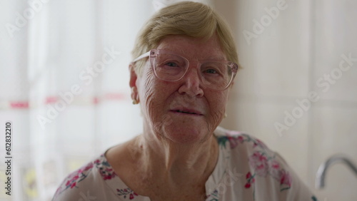 Portrait of an elderly caucasian senior woman close-up face looking at camera indoors. Older female person in 80s