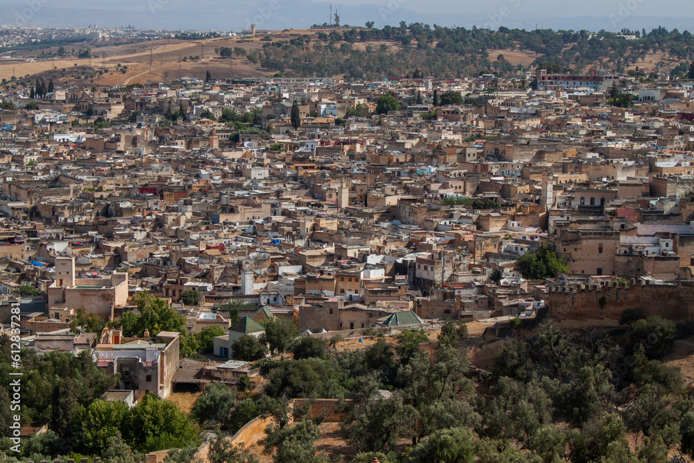 Aerial city view of the old Medina (downtown neighborhood) in Fez, Morocco, Africa. Rooftop view of Mosque towers and traditional Arabic townhouses. African urban landscape with historical buildings.