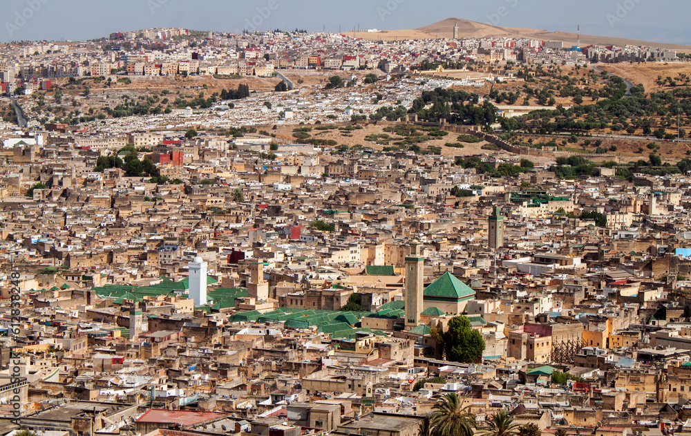 Aerial city view of the old Medina (downtown neighborhood) and the minaret of Zaouia Moulay Idriss II in Fez, Morocco, Africa. Rooftop view of Mosque towers and traditional Arabic townhouses.