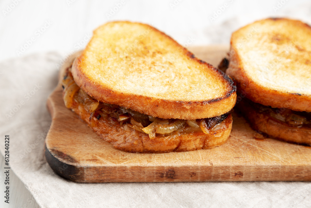 Homemade French Melt Sandwich with Caramelized Onion and Gruyure Cheese on a rustic wooden board, side view. Close-up. Homemade French Melt Sandwich with Caramelized Onion and Gruyure Cheese on a rustic wooden board, side view. Close-up.