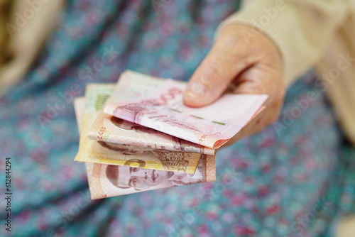 Asian elder senior woman patient holding banknotes money in her hand, Cost of living and medical care.