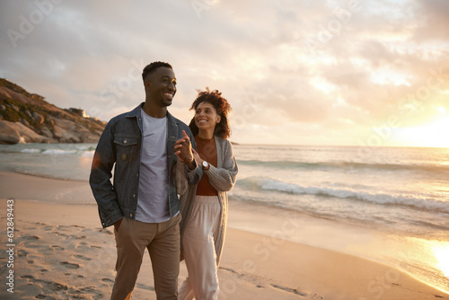Smiling young multiethnic couple walking along a beach at sunset