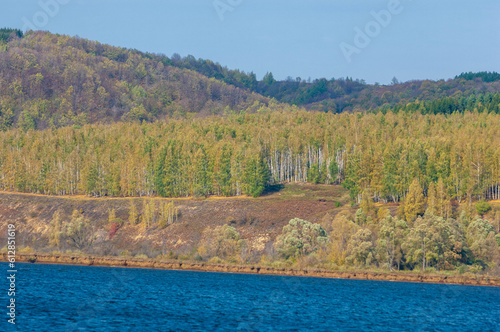 Photo of an autumn landscape, Picturesque autumn landscape of steady river and bright trees.
